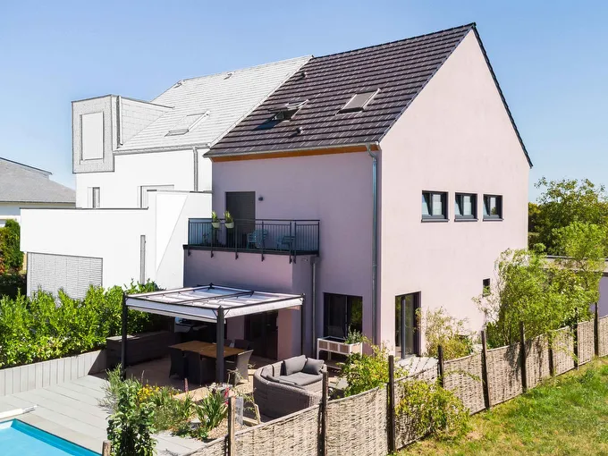 Fertighaus Doppelhaus mit Satteldach, Balkon, überdachter Terrasse und Garten in Außenansicht.