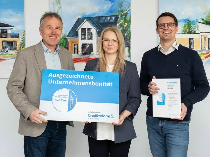 STREIF Unternehmensauszeichnung mit drei Personen, Bonitätszertifikat und Auszeichnungstafel vor gemalten Häusern