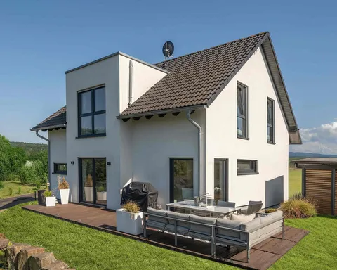 Fertighaus Einfamilienhaus Außenansicht mit Satteldach, heller Fassade und Terrasse im Garten