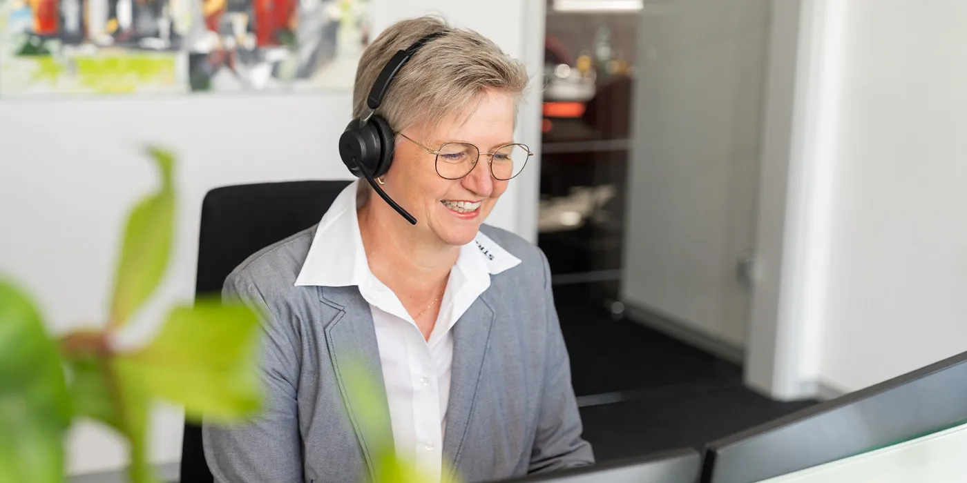 STREIF-Mitarbeiterin telefoniert mit einem Kunden und lächelt.
