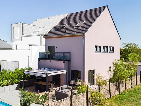Fertighaus Doppelhaus mit Satteldach, Balkon, überdachter Terrasse und Garten in Außenansicht.
