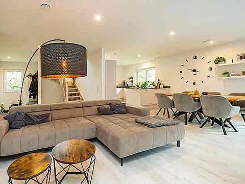 STREIF Innenraum moderner offener Wohn- und Essbereich mit grauem Sofa, Kücheninsel, Esstisch und Treppe