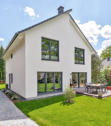 Fertighaus Einfamilienhaus mit Satteldach, heller Fassade und Terrasse im Garten