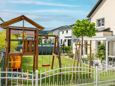 Fertighaus Einfamilienhaus mit Garten, Spielturm, Schaukel und Terrasse in Wohnsiedlung