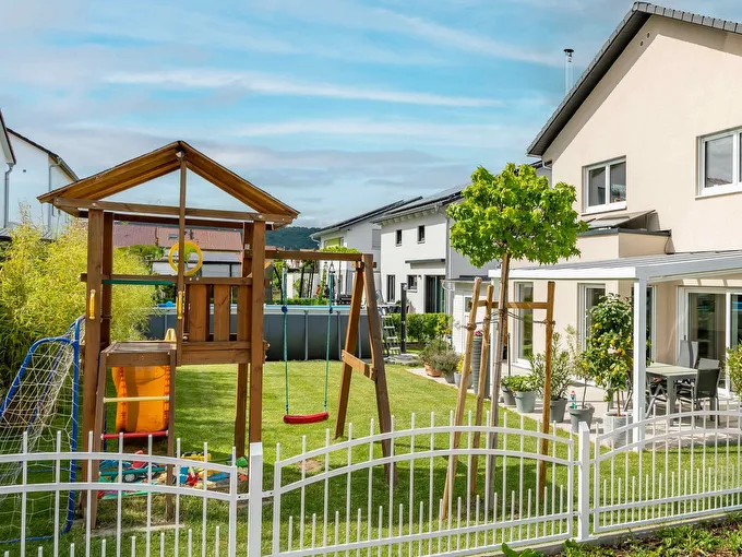 Fertighaus Einfamilienhaus mit Garten, Spielturm, Schaukel und Terrasse in Wohnsiedlung