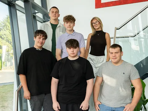 Auszubildende STREIF sechs neue Azubis posieren gemeinsam im hellen Treppenhaus vor einer Glasfassade