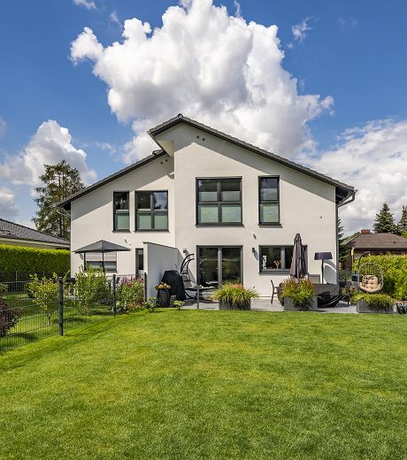 Fertighaus Einfamilienhaus mit Satteldach, weißer Fassade und großem Garten