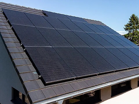 Fertighaus Einfamilienhaus mit geneigtem Dach und großflächiger Photovoltaikanlage in schräger Außenansicht