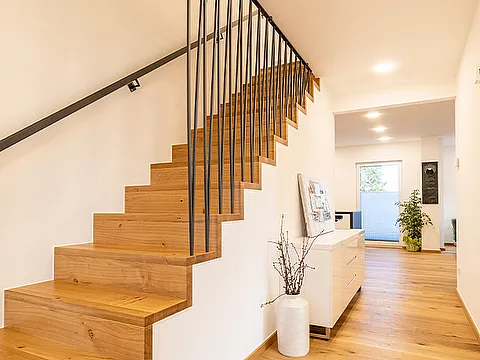 Geschlossene Faltwerktreppe aus Holz mit schwarzen Stäben im Flur mit Sideboard und Tageslicht