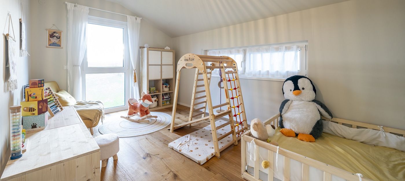 Kinderzimmer mit Klettergerüst, Bett, Spielzeug, Holzfußboden und großen Fenstern