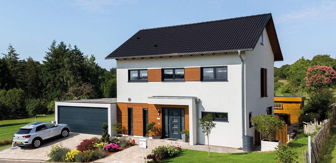 Fertighaus Einfamilienhaus mit Satteldach, weißer Putzfassade, Holzakzenten, Rechteckfenstern, Garage und Garten