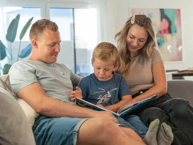 STREIF Innenraum Familie liest gemeinsam auf Sofa im hellen Wohnbereich