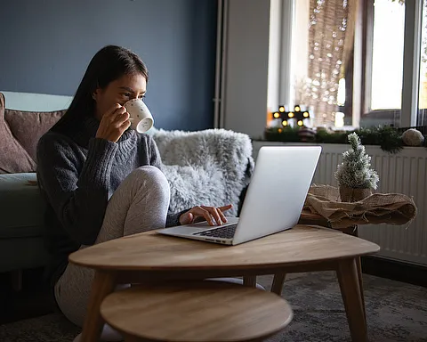 Eine junge Frau mit Laptop die sich im Internet informiert