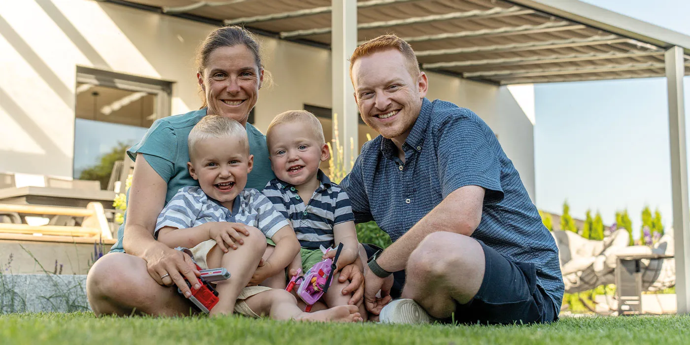 STREIF Baufamilie sitzt im Sommer vor einer modernen Stadtvilla mit Terrassenüberdachung
