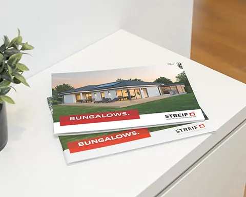 STREIF Katalog Bungalows auf weißem Tisch und grüner Zimmerpflanze