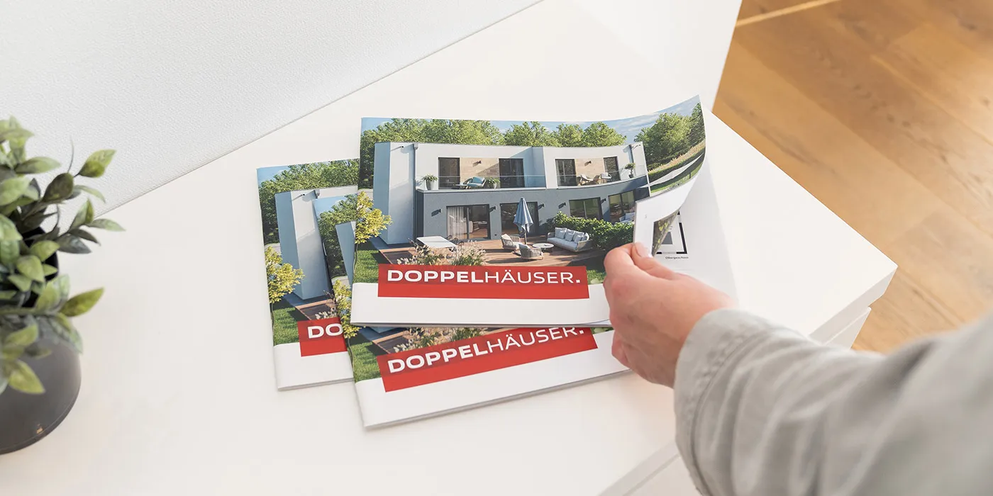 STREIF Katalog Doppelhaus mit Hausmotiv auf Tisch und Hand beim Umblättern