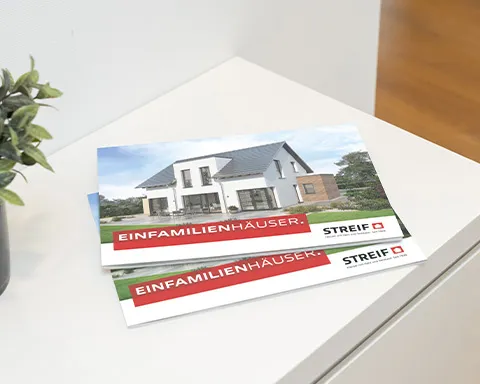 STREIF Einfamilienhaus Katalog liegt auf weißem Tisch mit Hausabbildung und rotem Titelbereich