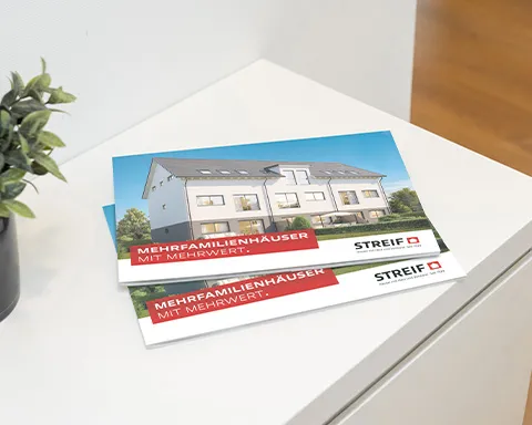 Gedrucktes Mehrfamilienhausprospekt von STREIF liegt auf weißen Sideboard