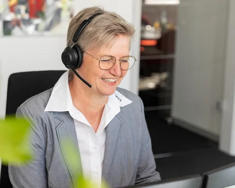 Mitarbeiterin STREIF sitzt am Empfang mit Telefonhörer im hellen Büro