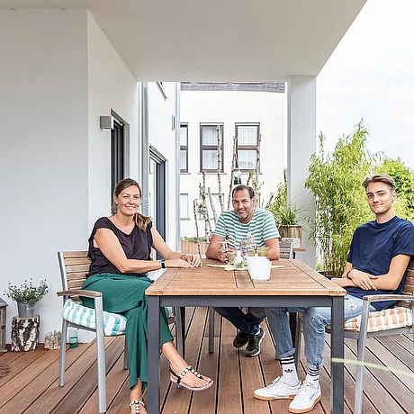 STREIF Situation Familie sitzt auf Terrasse am Gartentisch vor geöffneten Türen