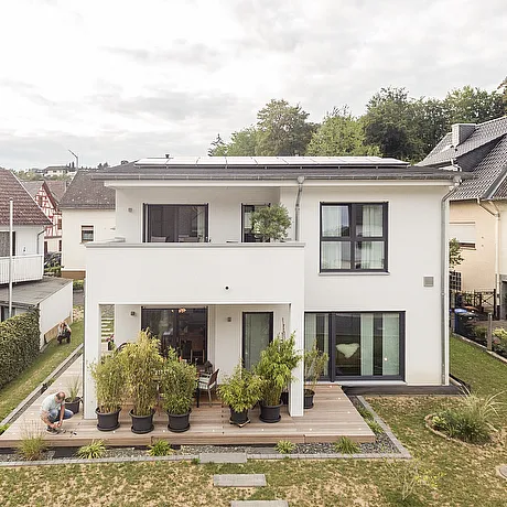 Fertighaus Stadtvilla mit Balkon, Terrasse und Garten in frontaler Außenansicht