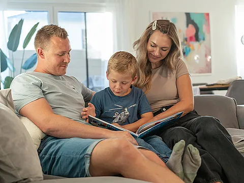 STREIF Innenraum Familie liest gemeinsam auf Sofa im hellen Wohnbereich