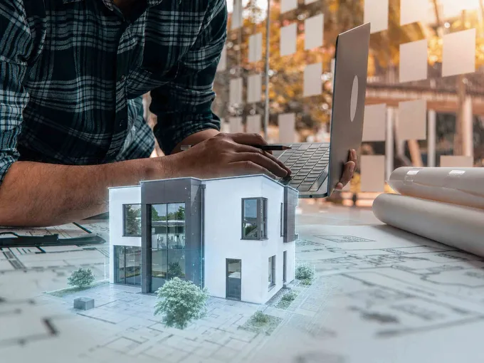 Fertighaus Stadtvilla als digitales Modell auf Bauplan mit Laptop im Planungsbüro